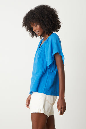 a woman wearing a Velvet by Graham & Spencer BELLE COTTON GAUZE BLOUSE top and white shorts.