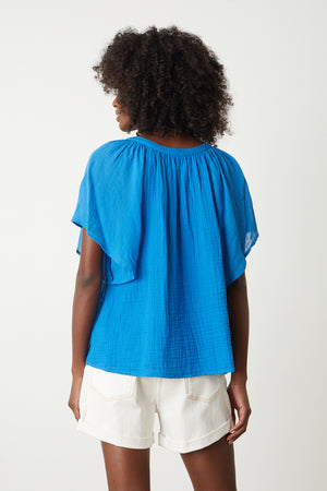 the back view of a woman wearing a Velvet by Graham & Spencer BELLE COTTON GAUZE BLOUSE and shorts.