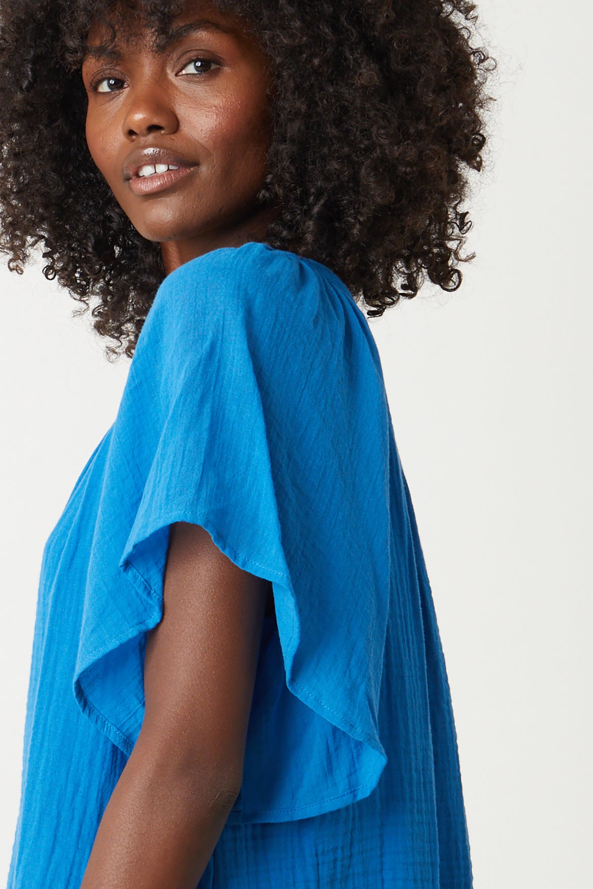 The model is wearing a Velvet by Graham & Spencer Belle Cotton Gauze Blouse with ruffled sleeves.