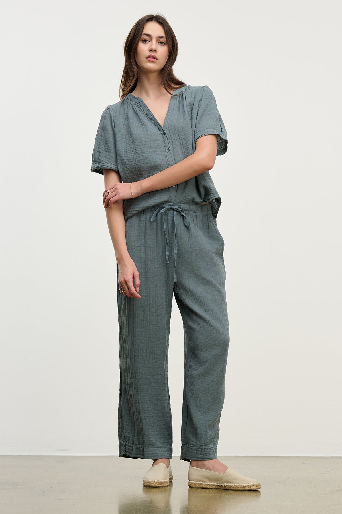 Wearing Velvet by Graham & Spencer's FRANNY COTTON GAUZE PANT with a relaxed leg and drawstring waist, a person stands against a plain background. The look is paired perfectly with flat, light-colored shoes.-38662569459905