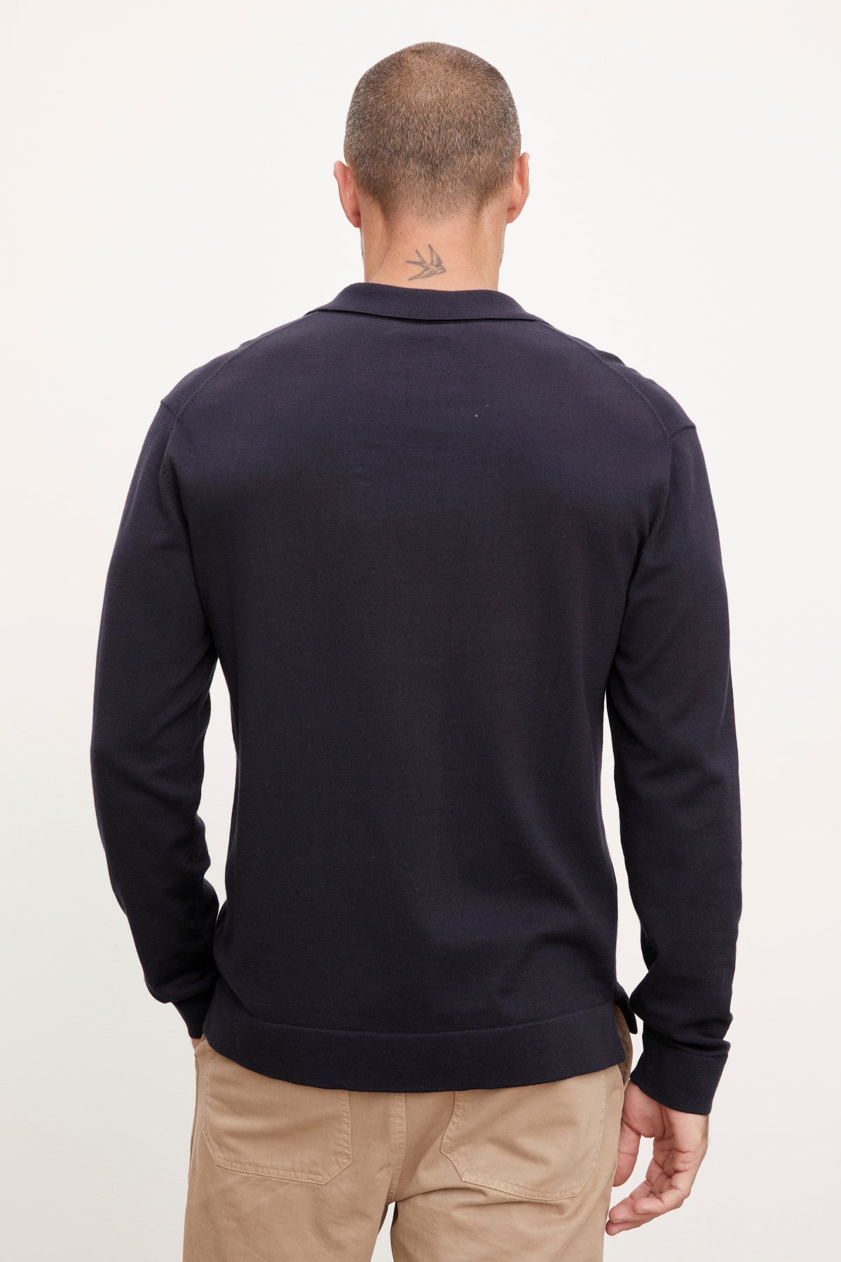   The back view of a man wearing a Velvet by Graham & Spencer navy sweater and khaki pants. 