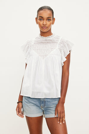 The model is wearing a Velvet by Graham & Spencer INESSA COTTON LACE TOP with ruffled sleeve.