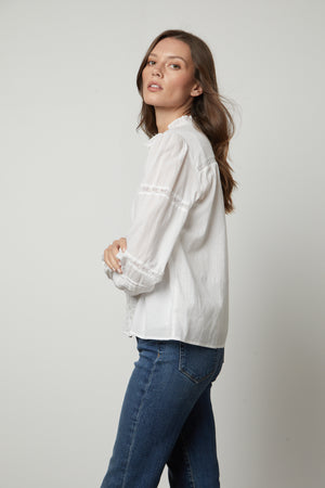 The model is wearing a Velvet by Graham & Spencer ROMY LACE BOHO TOP and jeans.