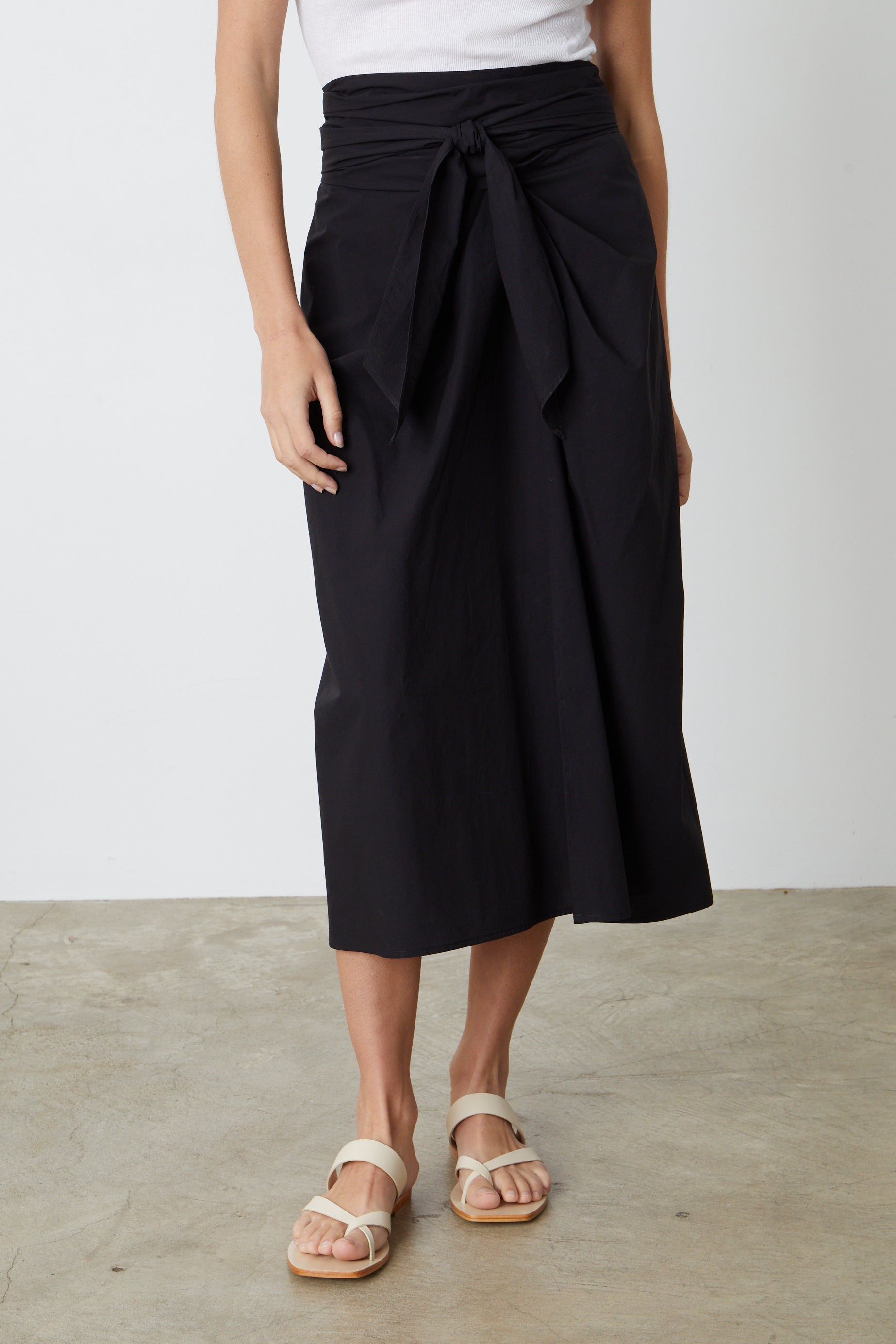 A person wearing the Velvet by Graham & Spencer LEENA TIE FRONT SKIRT and white sandals in the summer style.