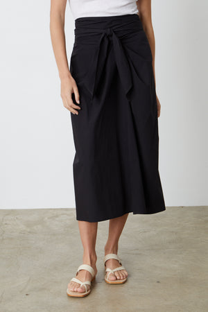 A person wearing the Velvet by Graham & Spencer LEENA TIE FRONT SKIRT and white sandals in the summer style.
