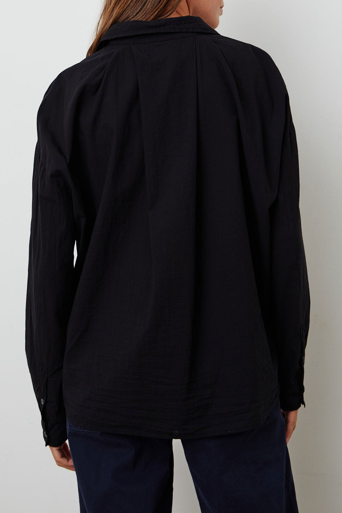 Person wearing a long-sleeved black DEVYN BUTTON-UP SHIRT by Velvet by Graham & Spencer and dark pants, viewed from the back.-37229064061121