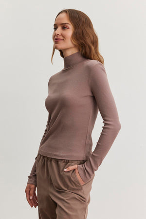 An individual dressed in the ADRIAN TEE by Velvet by Graham & Spencer and matching pants, standing against a plain background.