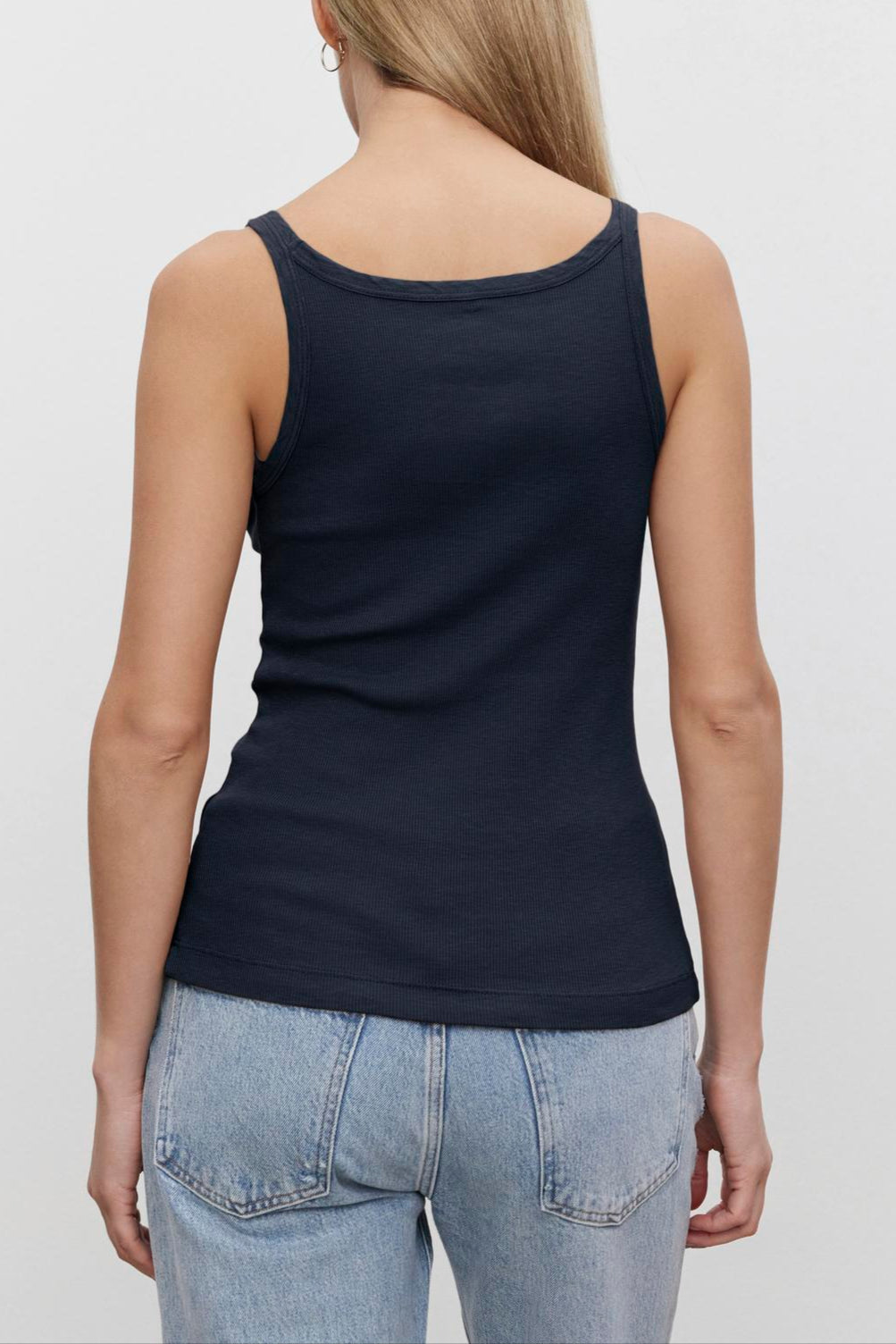 A woman viewed from behind wearing a Velvet by Graham & Spencer ALIZA RIBBED COTTON LAYERING TANK with double-layer straps and light blue jeans, standing against a plain white background.-36580672897217