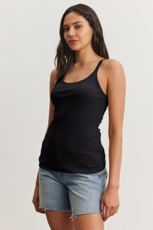 A person in an ALIZA Ribbed Cotton Layering Tank by Velvet by Graham & Spencer, paired with denim shorts, stands against a plain background.