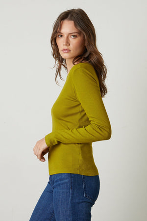 The model is wearing a Velvet by Graham & Spencer BAYLER RIBBED SCOOP NECK TEE and jeans.