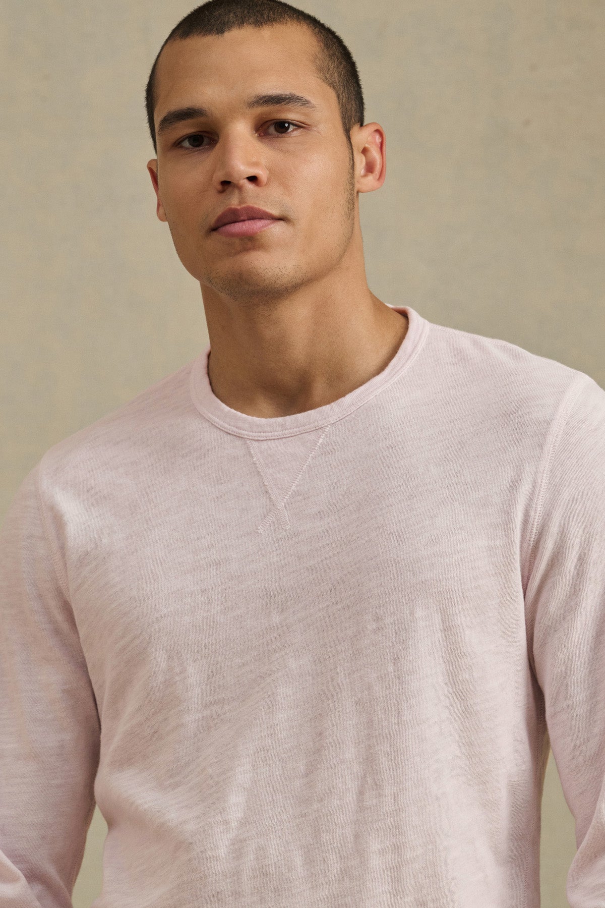 A person with short hair wears the ZANE TEE by Velvet by Graham & Spencer—a light pink, textured slub crew neck—while standing against a plain neutral background.-41480104378561