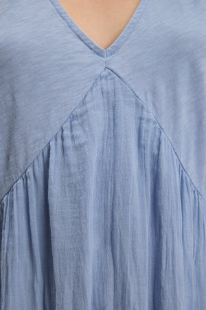 Close-up of the LILY DRESS by Velvet by Graham & Spencer, a light blue mini dress featuring a V-neck, relaxed fit, and gathered fabric detail below the neckline.