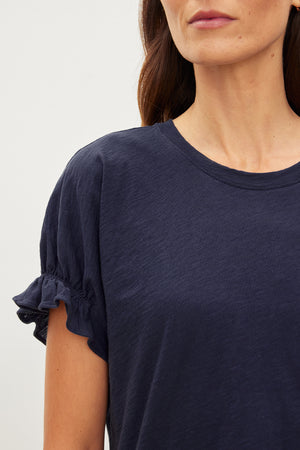 A woman wearing a navy cotton slub MIMI CREW NECK TEE with ruffle sleeves, an essential addition to her wardrobe with a crew neckline by Velvet by Graham & Spencer.