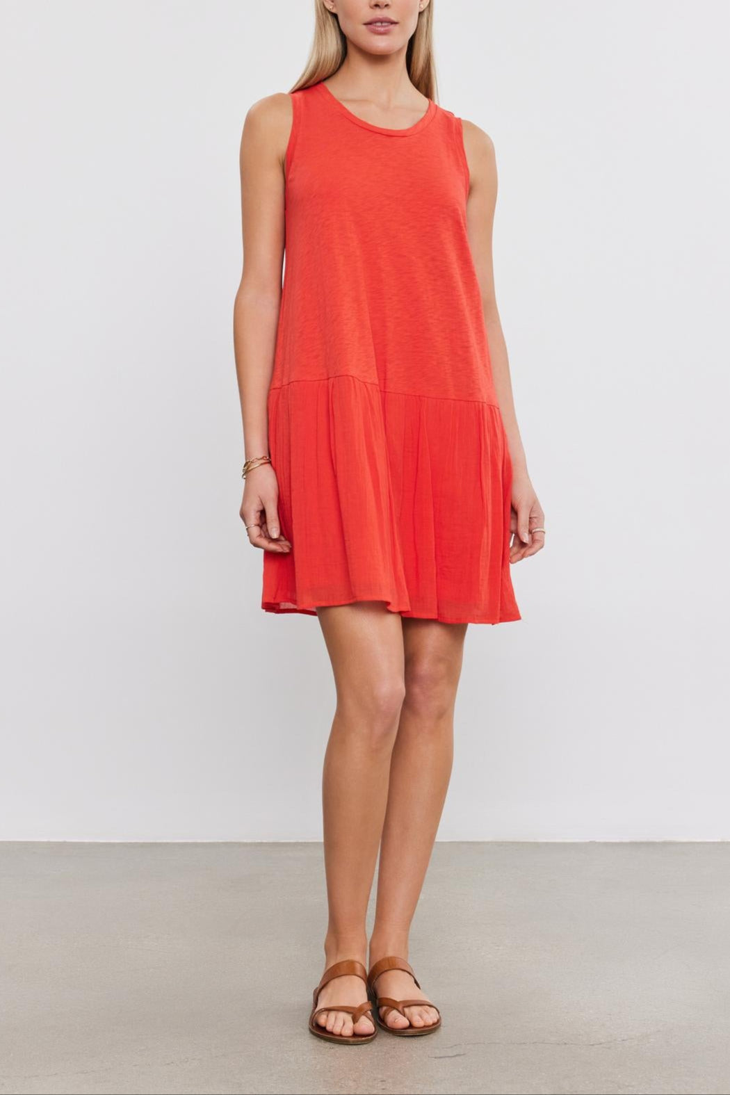 A woman wearing a Velvet by Graham & Spencer MINA DRESS with a tiered skirt and brown sandals stands against a plain white background.-36910021411009