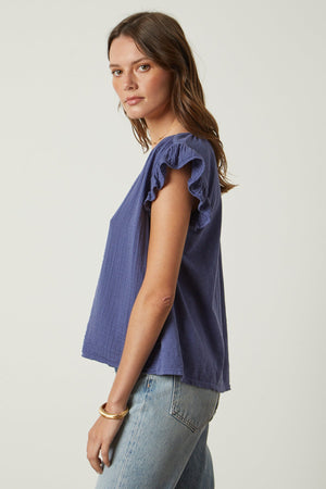 The model is wearing a REMI RUFFLE SLEEVE TOP by Velvet by Graham & Spencer.