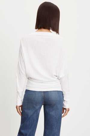 The view of a woman wearing Velvet by Graham & Spencer's NOVALEE DOLMAN TEE jeans and a white long sleeve top.