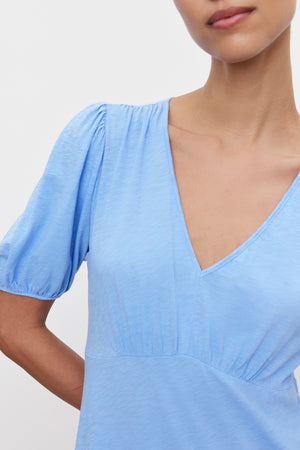 Close-up of a woman in a light blue Velvet by Graham & Spencer PARKER COTTON SLUB MIDI DRESS with gathered details, focusing on the neckline and sleeve.