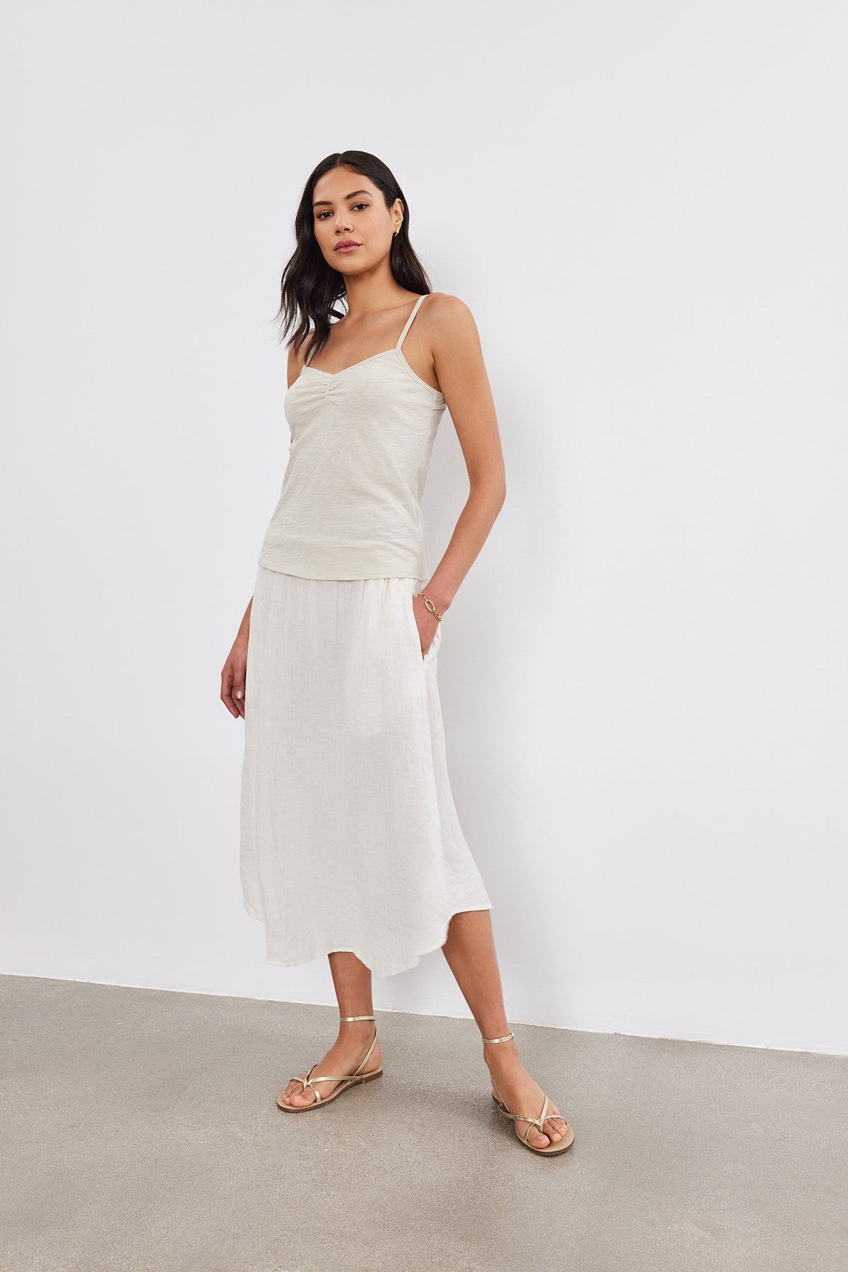 Woman wearing a Velvet by Graham & Spencer PEG TANK TOP with ruched detailing and a white midi skirt. She is standing against a plain white background.-37452679053505