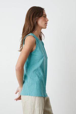 A woman wearing a turquoise Velvet by Graham & Spencer TAURUS COTTON SLUB TANK tank and Dru pants in sand side.