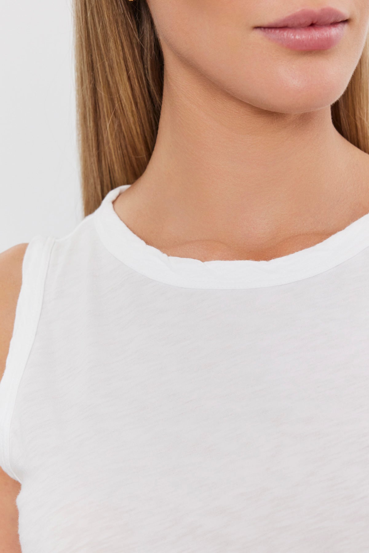 Person wearing a sleeveless white shirt stands against a plain background. The image shows the lower half of their face and upper body, highlighting the textured cotton slub of the Velvet by Graham & Spencer TAURUS TANK TOP—a versatile staple for any wardrobe.-35586089025729