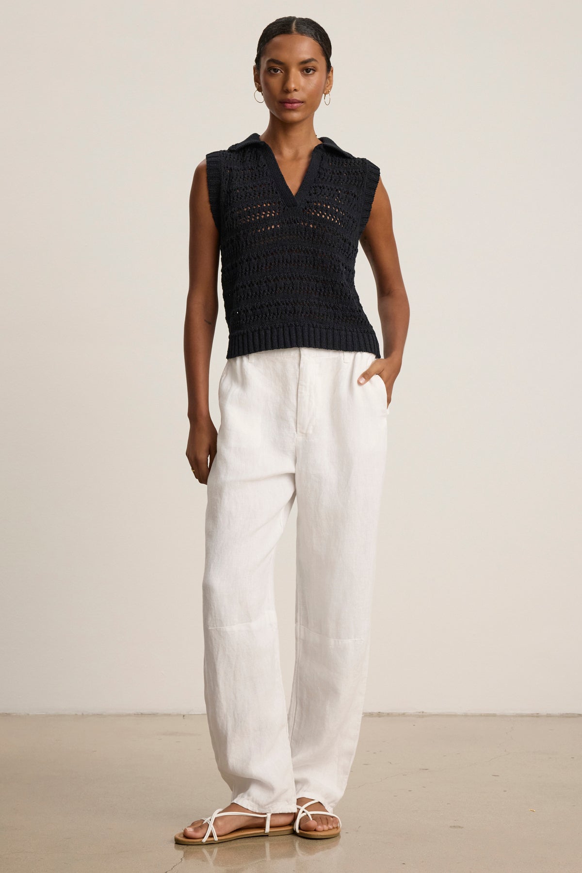 A woman in the RENEE SWEATER POLO by Velvet by Graham & Spencer, styled with white wide-leg pants and sandals, stands against a light background, showcasing breathable comfort.-39111850033345