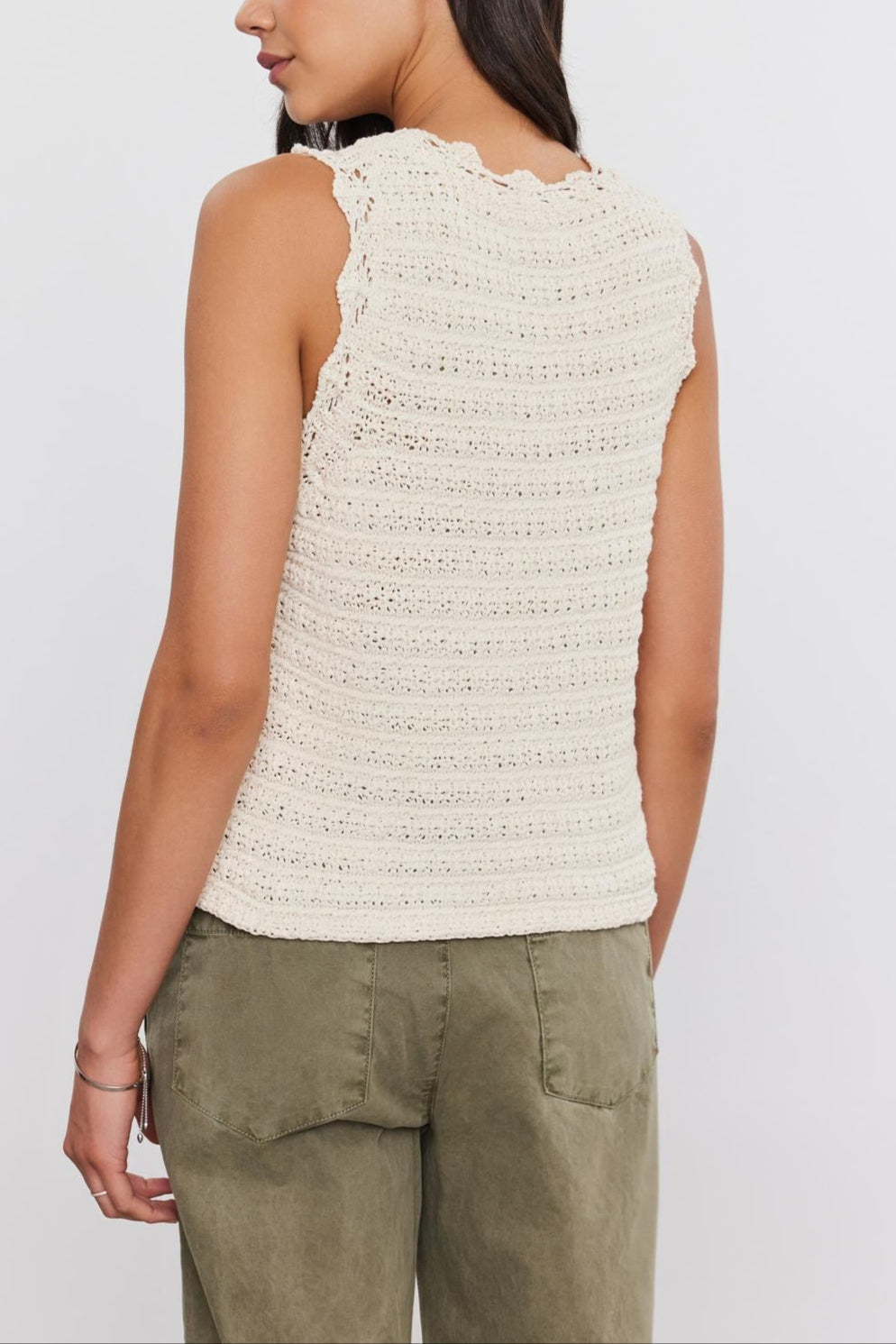 A woman with long dark hair is standing and facing away, wearing the SOPHIE SWEATER VEST by Velvet by Graham & Spencer and olive green pants.-37054560469185