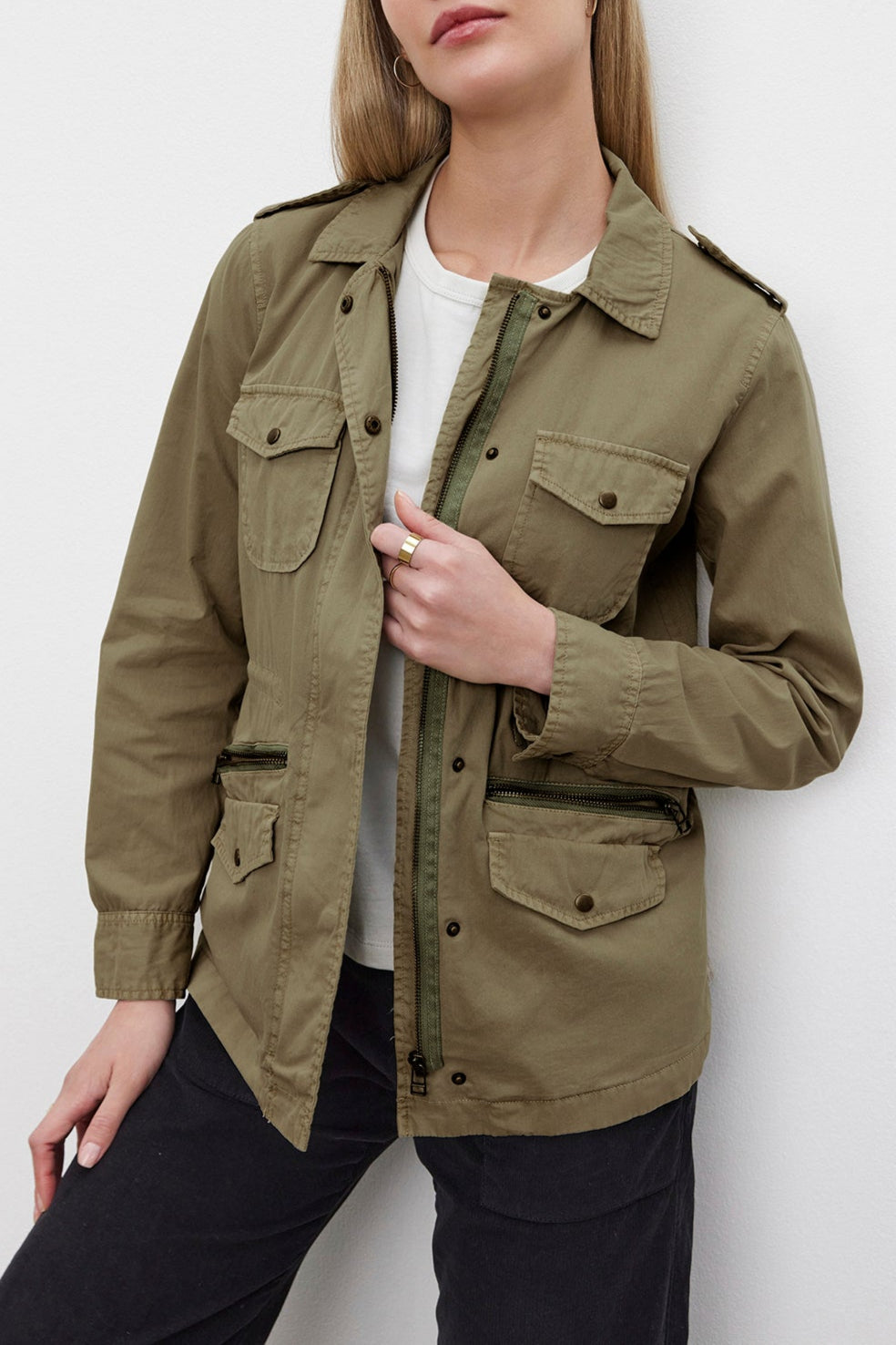 A person with long blonde hair wears the RUBY LIGHT-WEIGHT ARMY JACKET by Velvet by Graham & Spencer, crafted from olive green cotton twill, over a white shirt. They exude off-duty glamour while posing against a plain white background.-37959444168897