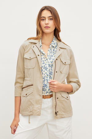 A woman wearing a RUBY LIGHT-WEIGHT ARMY JACKET in a tan shade to enhance her versatility, by Velvet by Graham & Spencer.