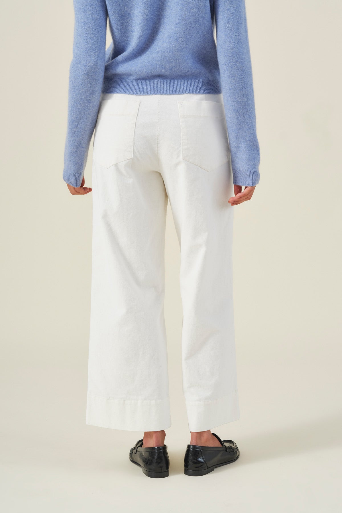 A person seen from behind, wearing a blue sweater and white high-rise wide-leg VERA CORDUROY PANT.-46489776685249