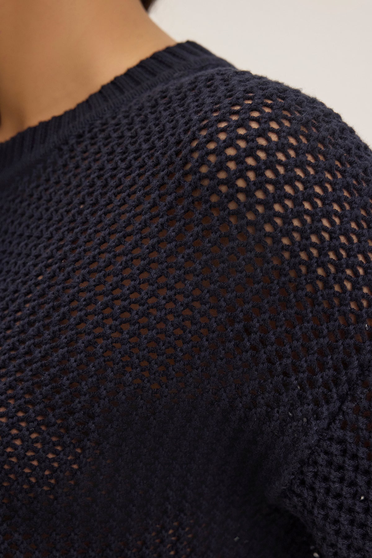 Close-up of someone in a Velvet by Graham & Spencer VIENNA COTTON CASHMERE MESH SWEATER, featuring a navy blue textured open-knit design, relaxed fit, and soft cotton cashmere blend.-38663172554945