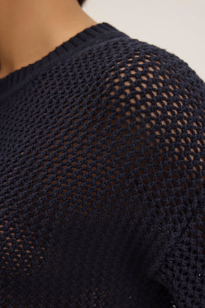 Close-up of someone in a Velvet by Graham & Spencer VIENNA COTTON CASHMERE MESH SWEATER, featuring a navy blue textured open-knit design, relaxed fit, and soft cotton cashmere blend.