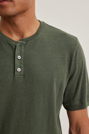 A person wearing the VITO HENLEY by Velvet by Graham & Spencer, a green shirt with buttons made from soft Peruvian cotton, facing forward.