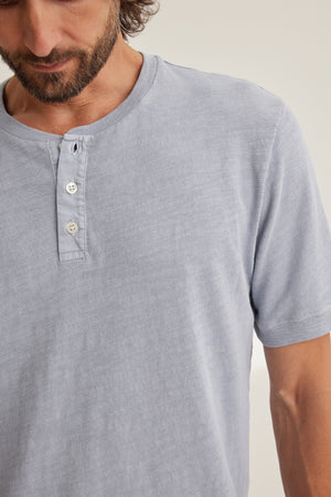 A man models the VITO HENLEY by Velvet by Graham & Spencer, a light gray Peruvian cotton short-sleeved shirt with a three-button design, shown from shoulders to mid-torso.