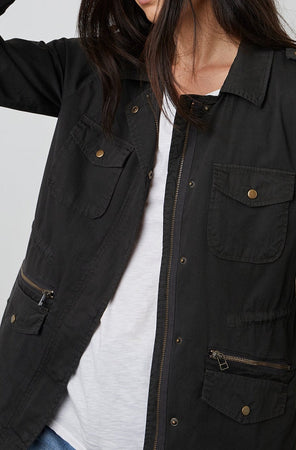A woman wearing a black Velvet by Graham & Spencer RUBY LIGHT-WEIGHT ARMY JACKET with zippers and pockets.