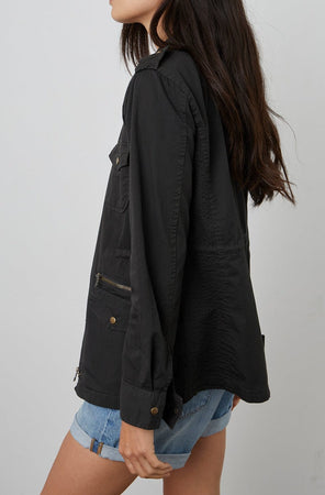 The back view of a woman wearing a Velvet by Graham & Spencer RUBY LIGHT-WEIGHT ARMY JACKET and shorts.
