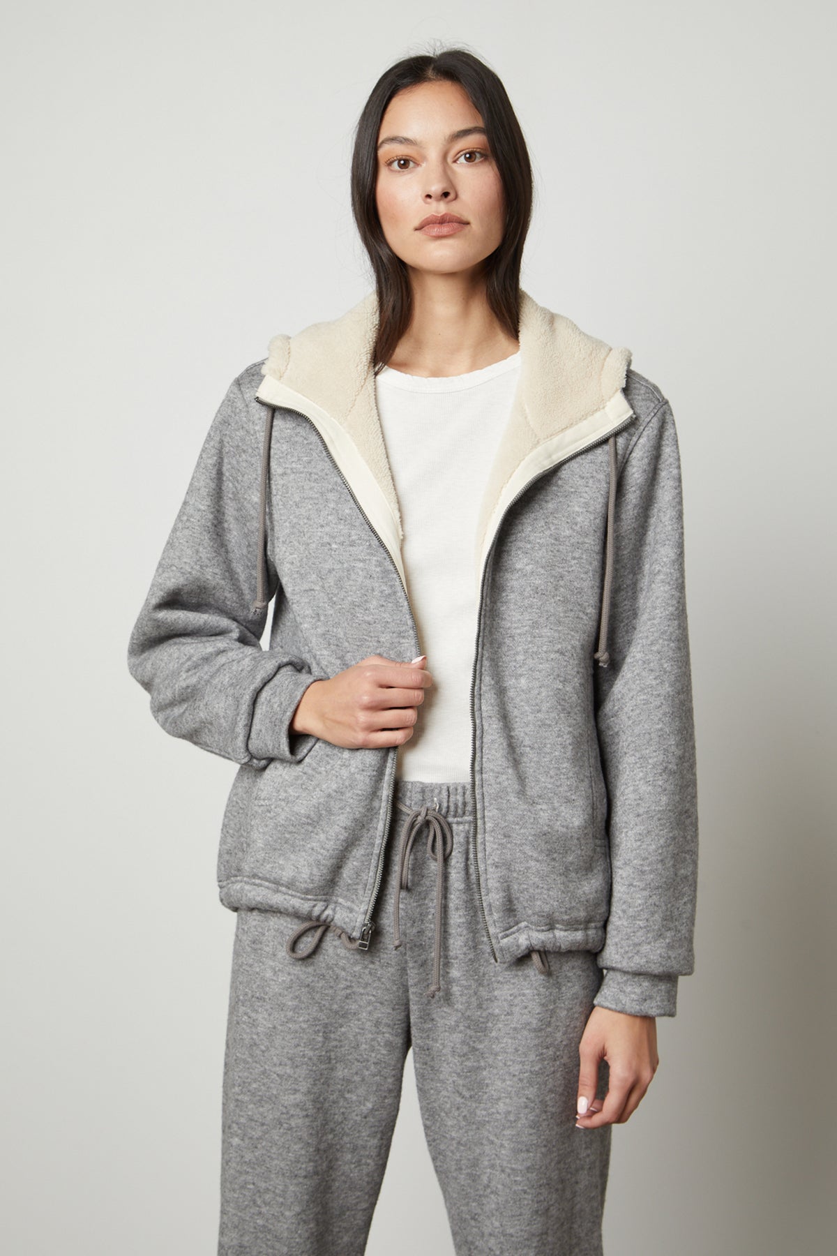 The model is wearing a Velvet by Graham & Spencer OCTAVIA DOUBLE KNIT ZIP UP HOODIE and sweatpants.