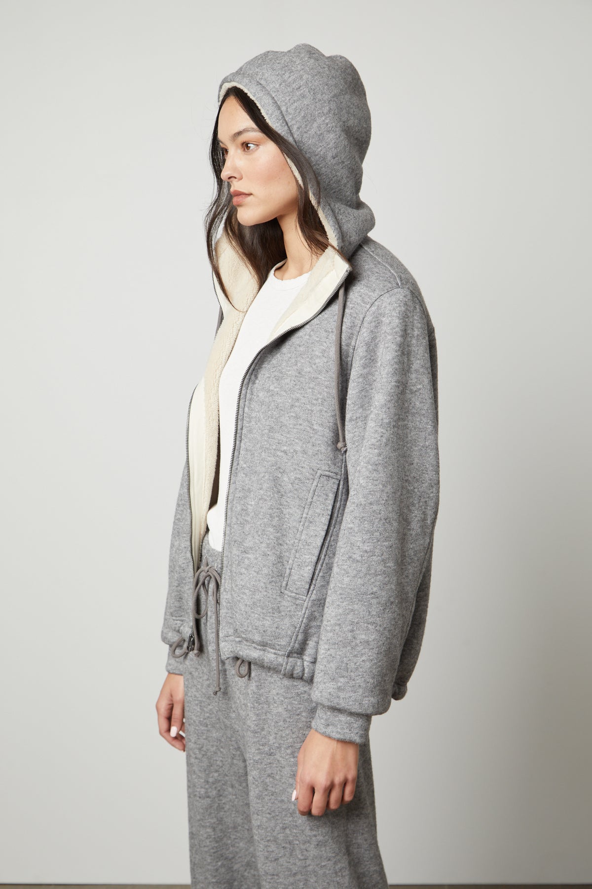 The model is wearing the Velvet by Graham & Spencer OCTAVIA DOUBLE KNIT ZIP UP HOODIE and sweatpants.