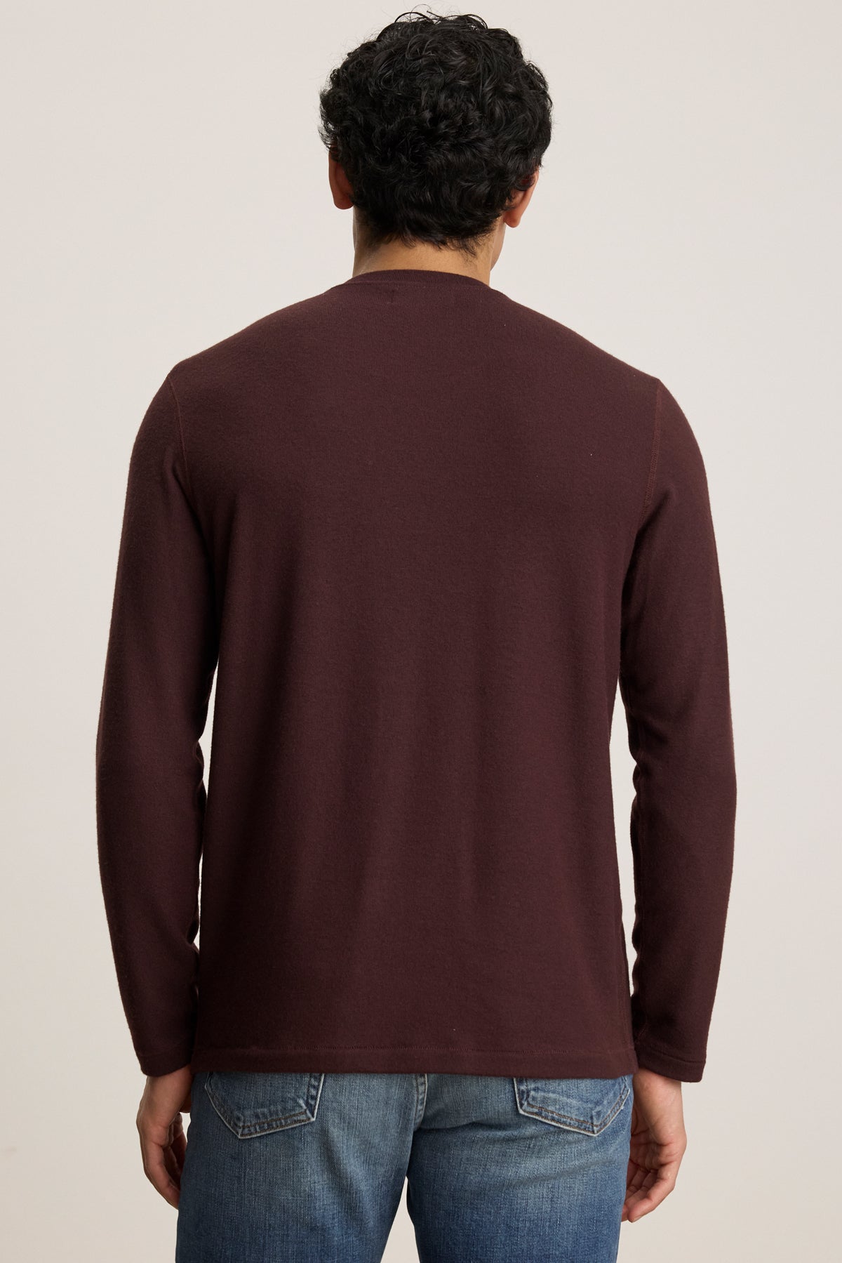A person is shown from the back against a plain background, wearing Velvet by Graham & Spencer’s BECKER CREW cozy maroon jersey long-sleeve shirt with blue jeans.-39905750810817