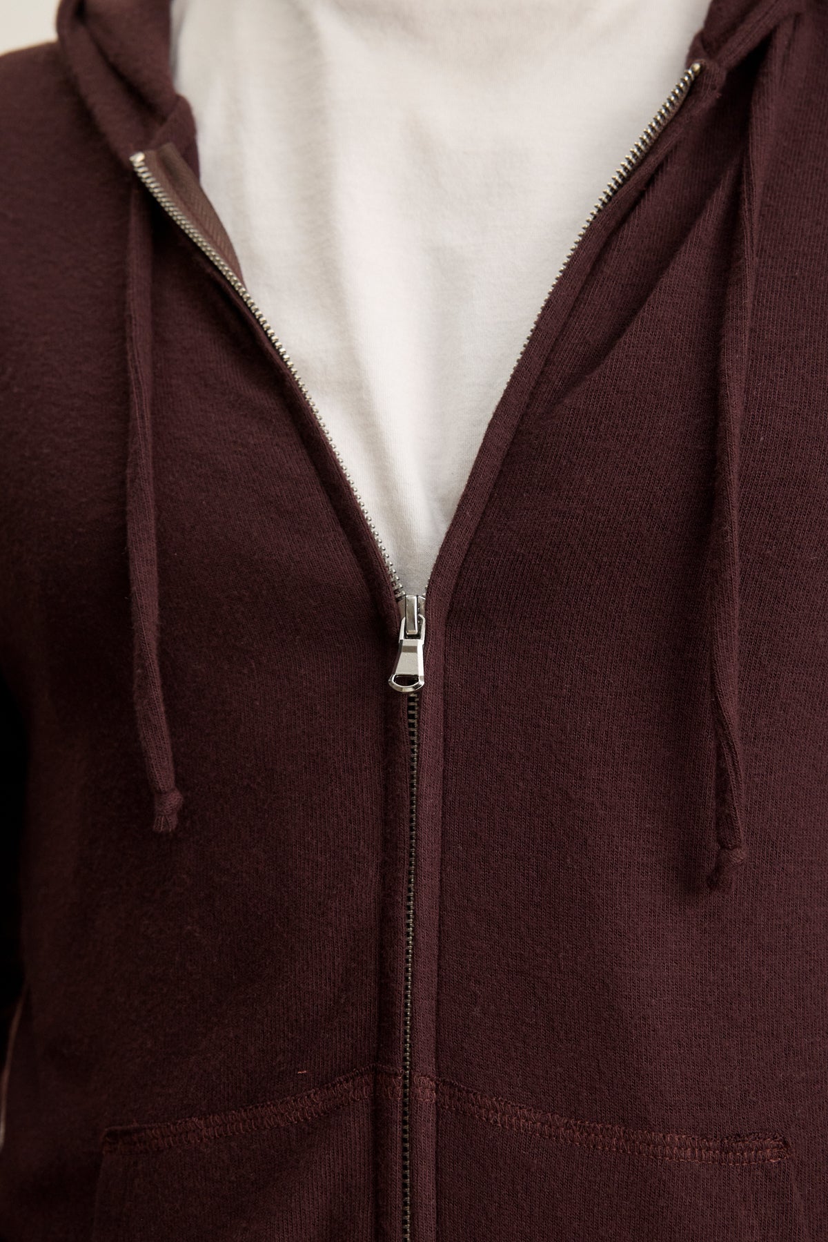 A person wears a white t-shirt under the Velvet by Graham & Spencer LOUDON HOODIE, a maroon triblend cozy jersey full-zip hoodie, with the zipper partially closed.-39905796817089