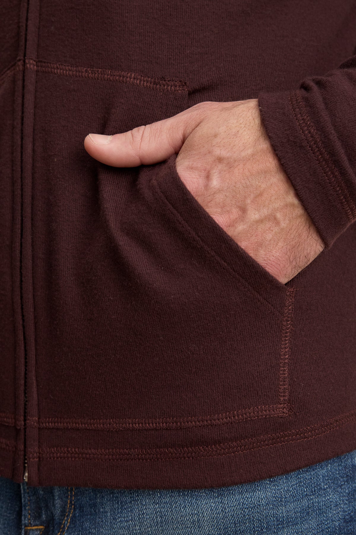 A person wearing the LOUDON HOODIE by Velvet by Graham & Spencer has their right hand in the hoodie’s pocket, paired with blue jeans.