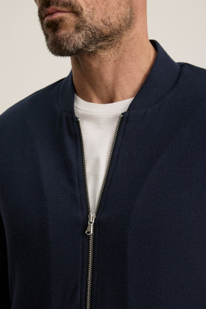 A man wearing the Velvet by Graham & Spencer MILES JACKET in navy blue over a white t-shirt, shown from shoulders to mid-chest.