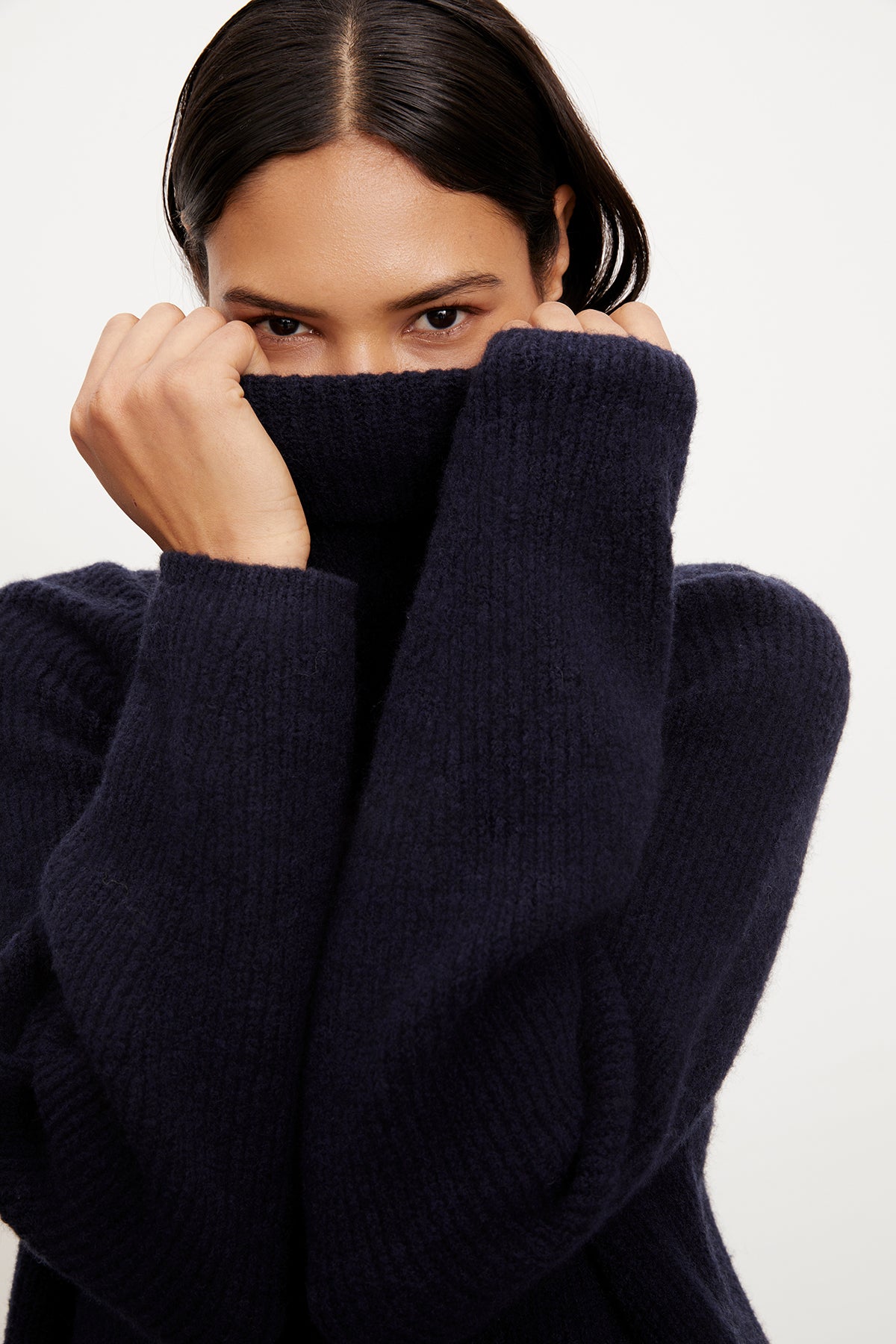 A woman in a Velvet by Graham & Spencer JUDITH turtleneck sweater, made of a wool blend, is cozily dressed.-35577840337089