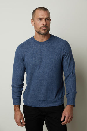 A man wearing a Velvet by Graham & Spencer PONCHO THERMAL CREW sweater and black pants, perfect for cooler days.