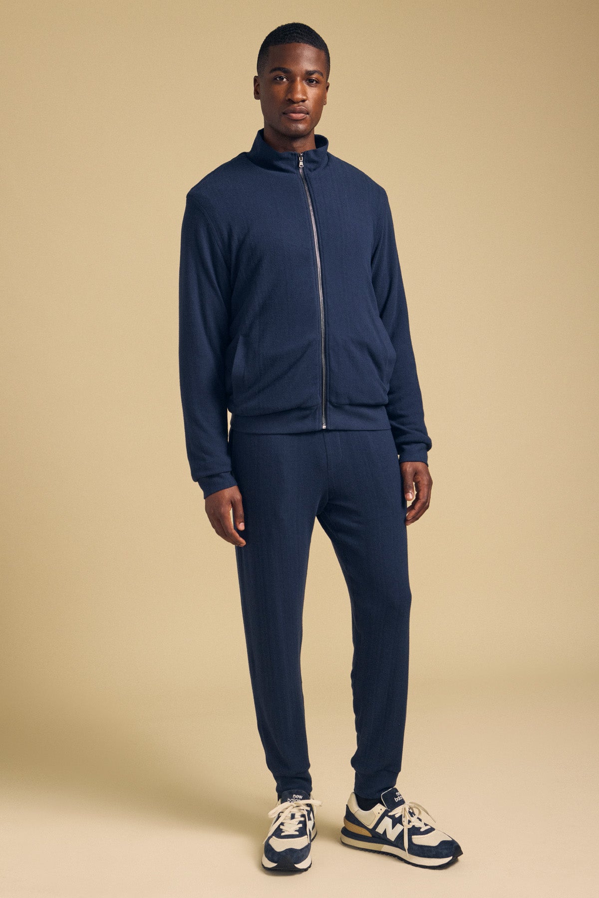A man wearing a navy NASH JACKET and matching joggers with blue and cream sneakers.-46288273342657