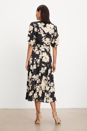 The back view of a woman wearing the Velvet by Graham & Spencer KAI PRINTED WRAP DRESS.