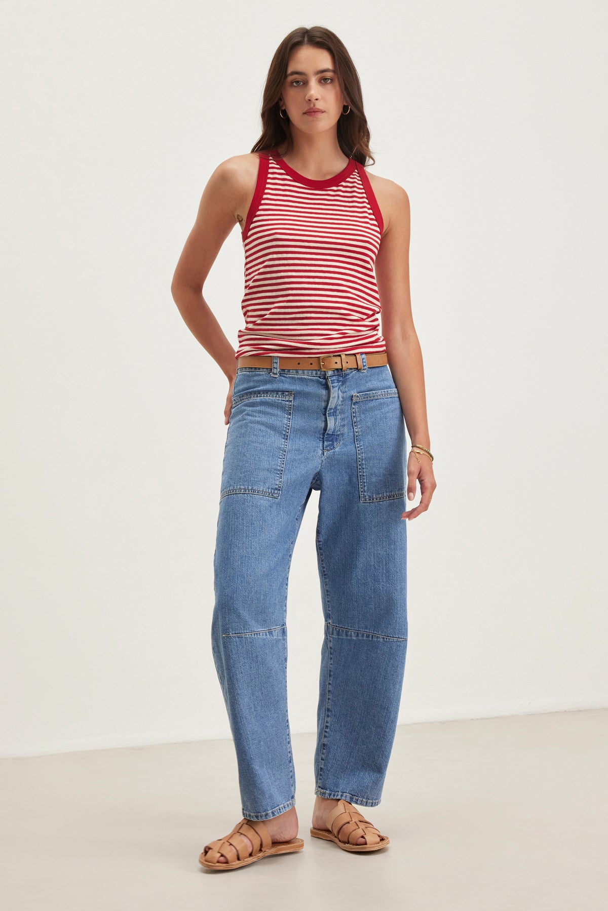 A person wearing a red and white striped sleeveless top, Velvet by Graham & Spencer's FARAH DENIM PANT, and brown sandals stands against a plain background.