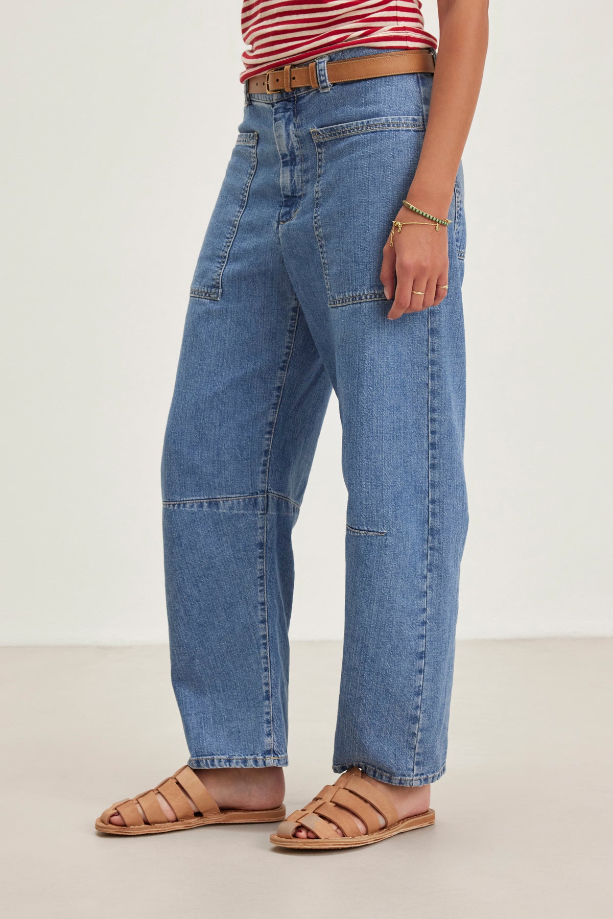 A person in Velvet by Graham & Spencer's FARAH DENIM PANT, a red and white striped top, and brown sandals stands against a plain background.