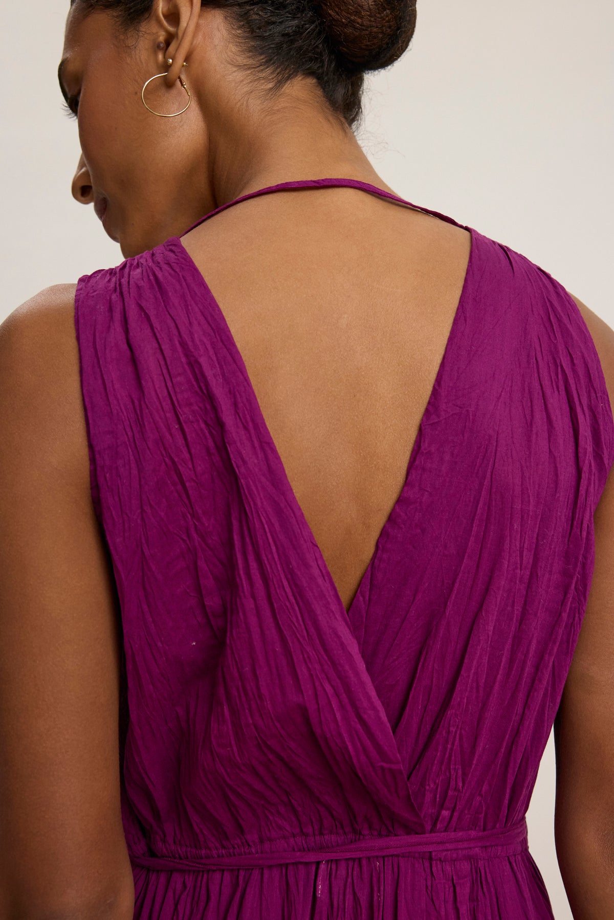 A person wearing the MARILYN DRESS by Velvet by Graham & Spencer—a sleeveless, deep purple dress featuring a feminine fit and deep V-shaped back—viewed from behind.