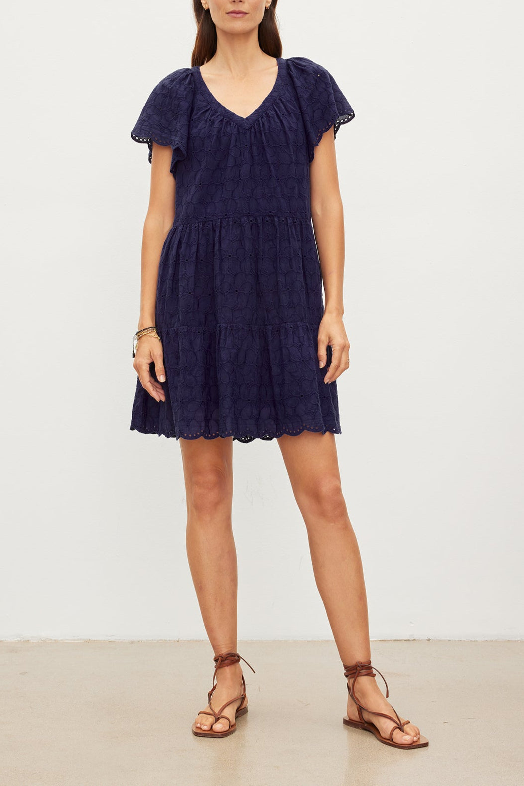 Woman in a WYNETTE EMBROIDERED COTTON DRESS by Velvet by Graham & Spencer, standing against a plain white background, paired with brown strappy sandals.-35967521620161