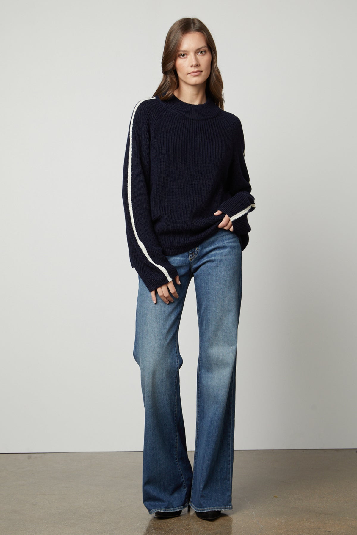 The model is wearing a TEAGAN MOCK NECK SWEATER by Velvet by Graham & Spencer and flared jeans.-26897832083649